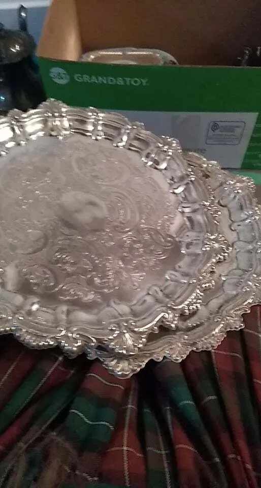 Large polished round silver serving platter with raised edge and embossed surface